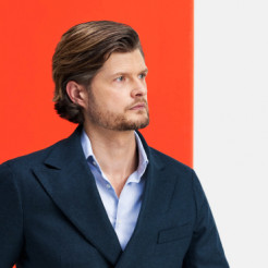 Porträt von Daniel Hiemer, Partner Tax bei Kirkland & Ellis in München, im Dreiviertelprofil mit blauem Sacco und hellblauem Hemd mit geöffnetem Kragen